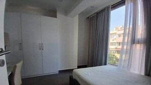 Une chambre d’hôtel avec un lit, un bureau et une armoire.