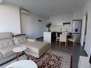 A modern living room with a sofa, a small round table, and a patterned rug. - Casa Bella (Maputo)