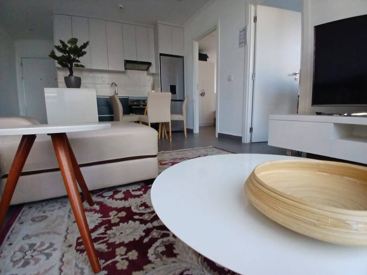 Een moderne woonkamer met een witte bank, een ronde salontafel en een televisie.