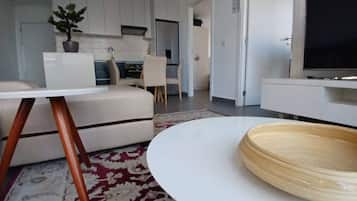 Een moderne woonkamer met een witte bank, een ronde salontafel en een televisie.