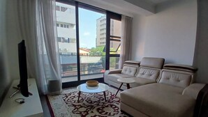 Un salon moderne avec un canapé, des fauteuils, une table basse et un téléviseur posé sur un meuble.