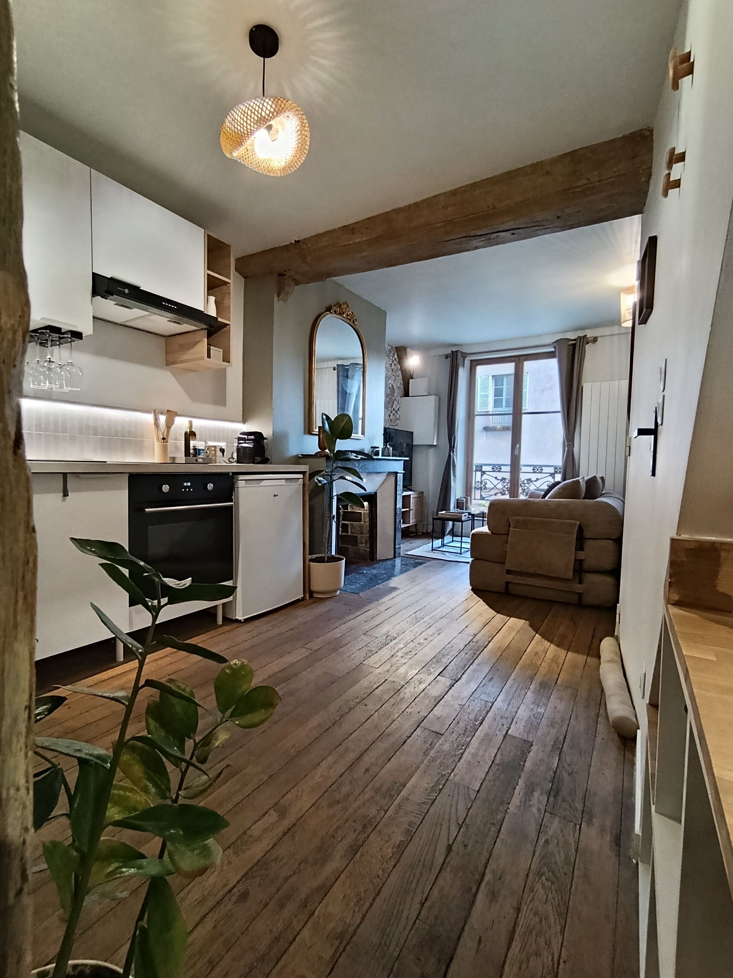 Une cuisine moderne avec un coin repas, un plancher en bois et un grand miroir.