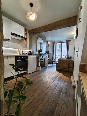 A modern kitchen with a dining area, wooden flooring, and a large mirror. - "Le Cathédrale" Jean Moulin, parking, city center (Chartres)