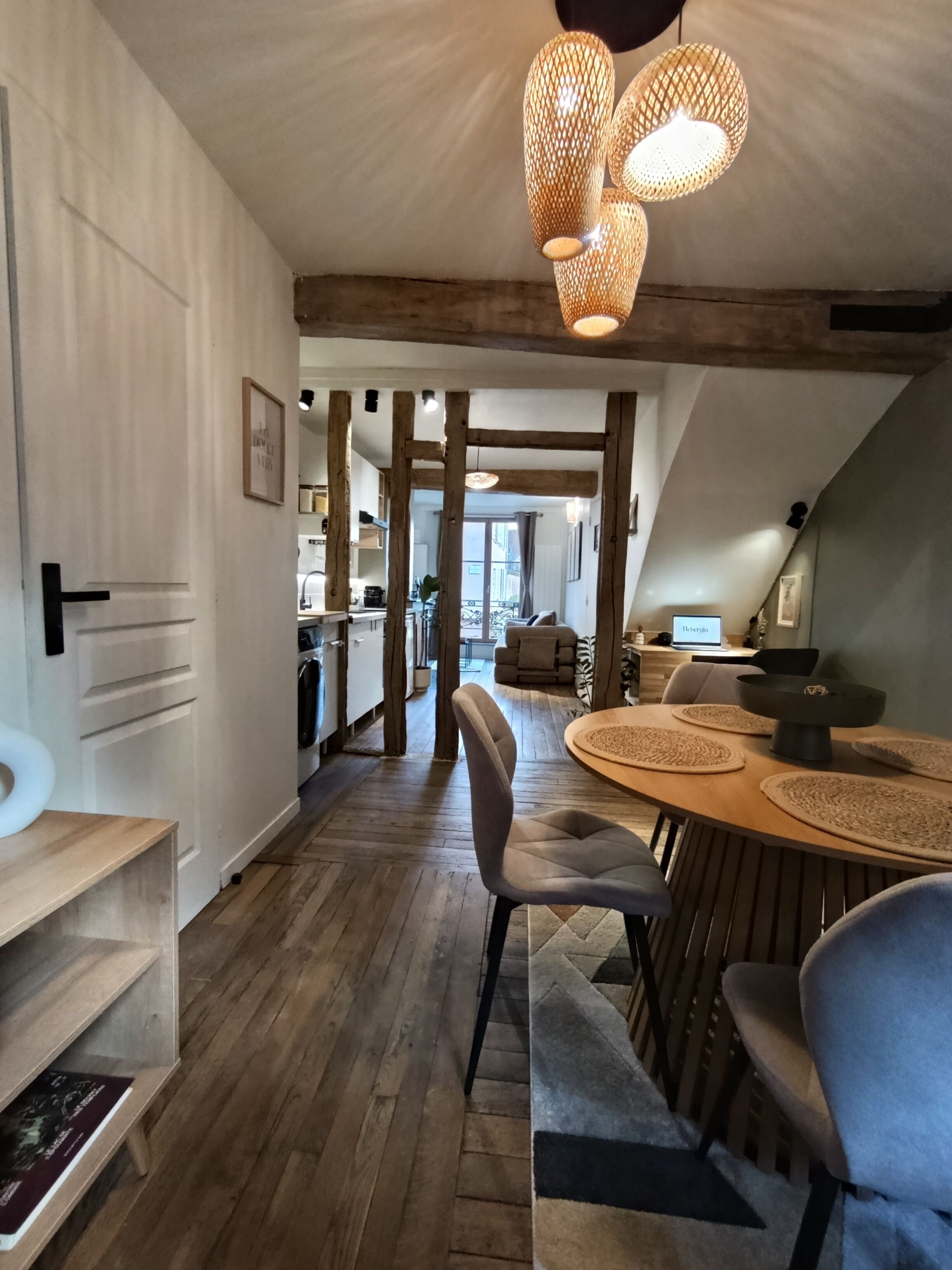 Een modern interieur met een houten vloer, een eetgedeelte met een ronde tafel, en een keuken op de achtergrond.