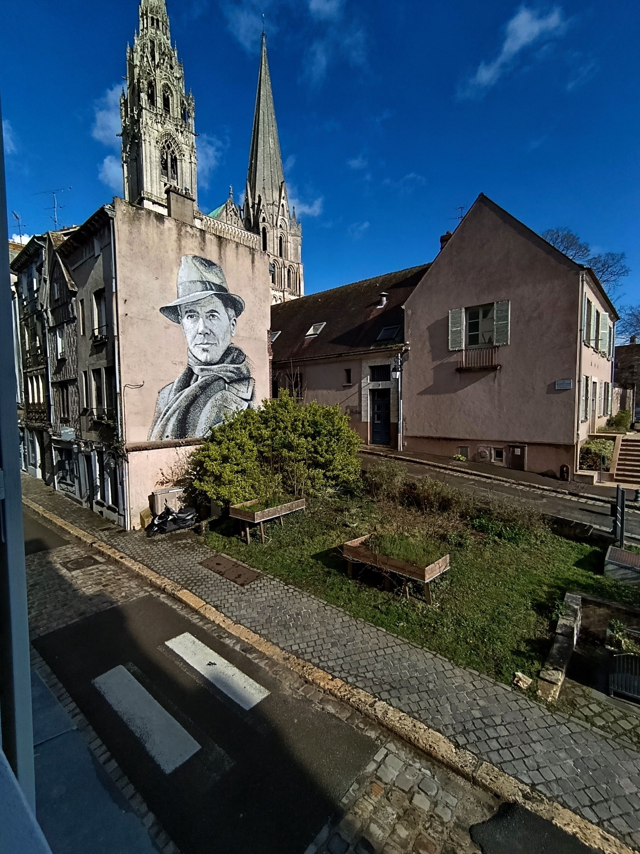 A street with a church, a mural, and a building with a balcony.