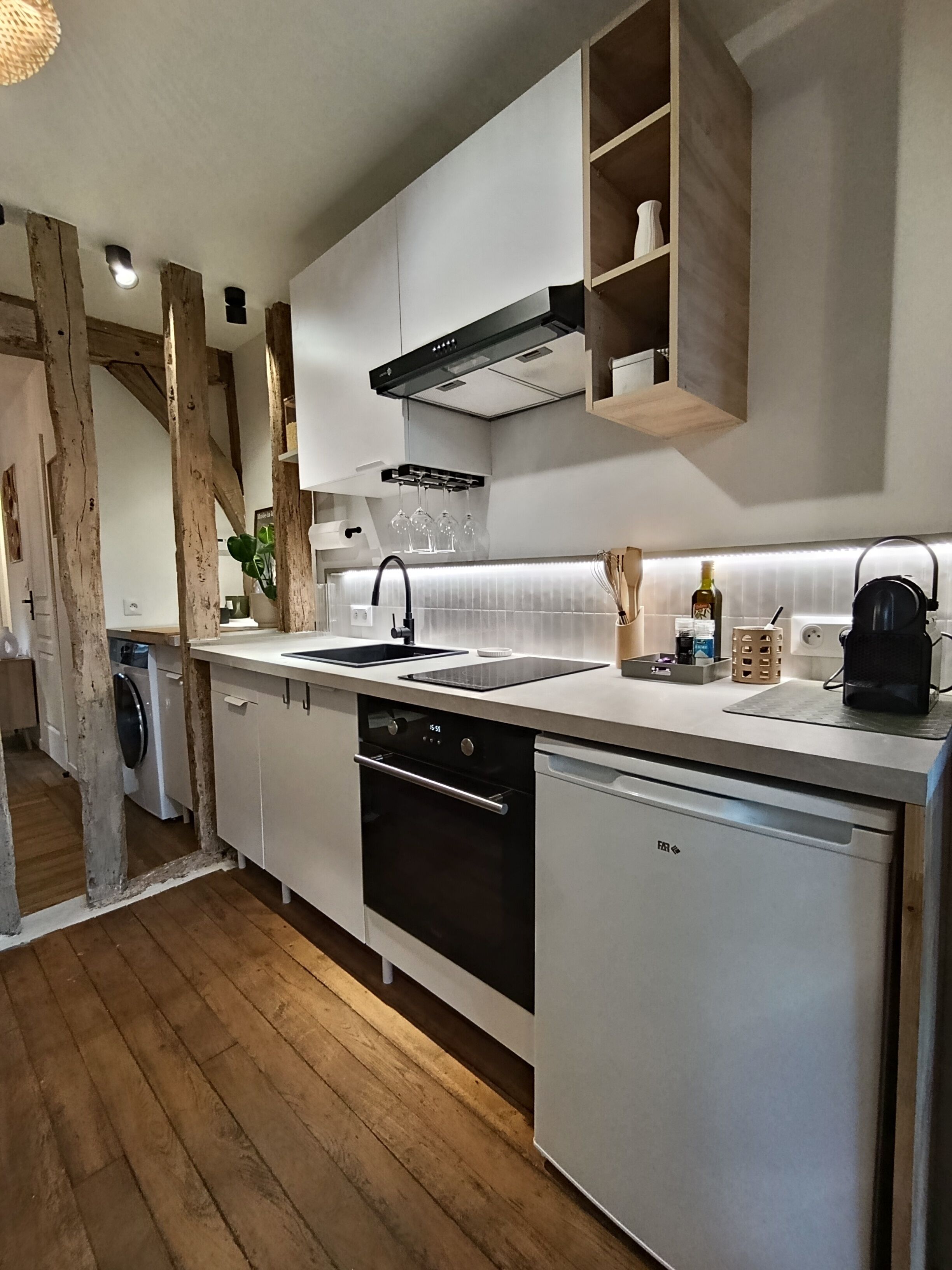 Een moderne keuken met witte kasten, een zwarte oven, een vaatwasser en houten balken.