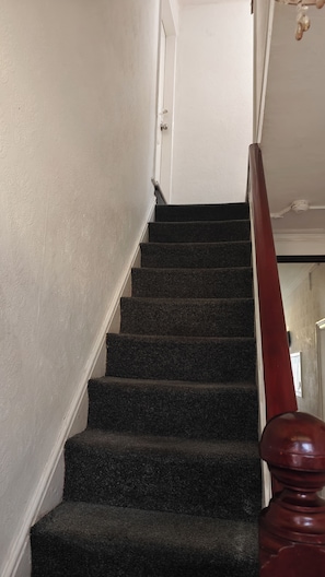 A staircase with carpeted steps leading to a door with a white wall. - Single room In Manchester's famous curry mile (Manchester)