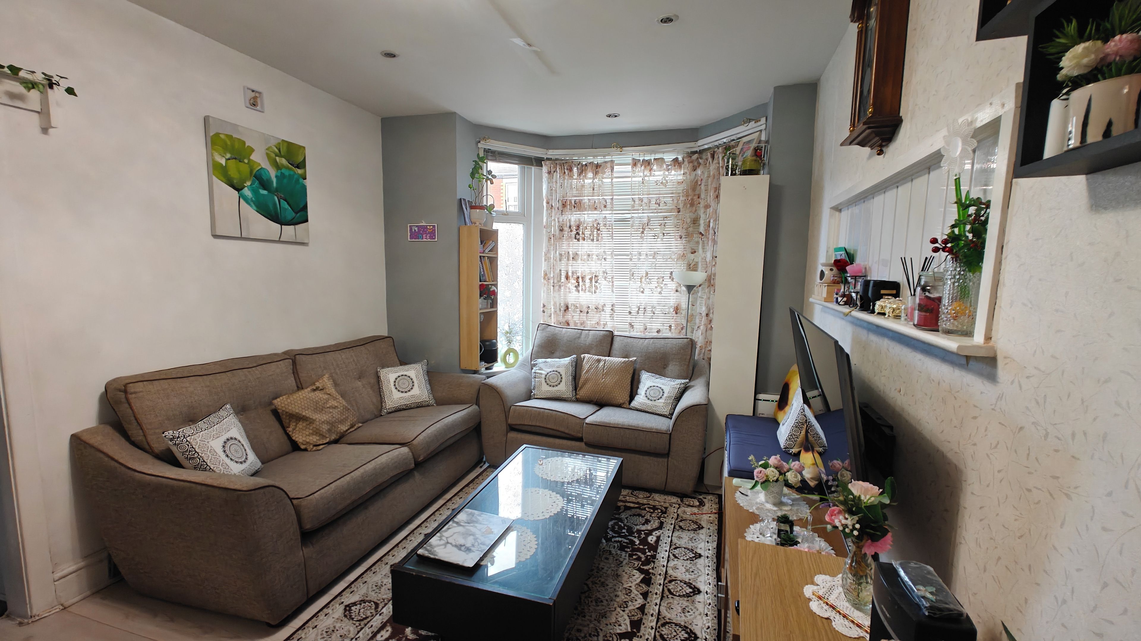 A living room with a sofa set, a coffee table, and a decorative vase with flowers.