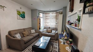 A living room with a sofa set, a coffee table, and a decorative vase with flowers. - Single room In Manchester's famous curry mile (Manchester)