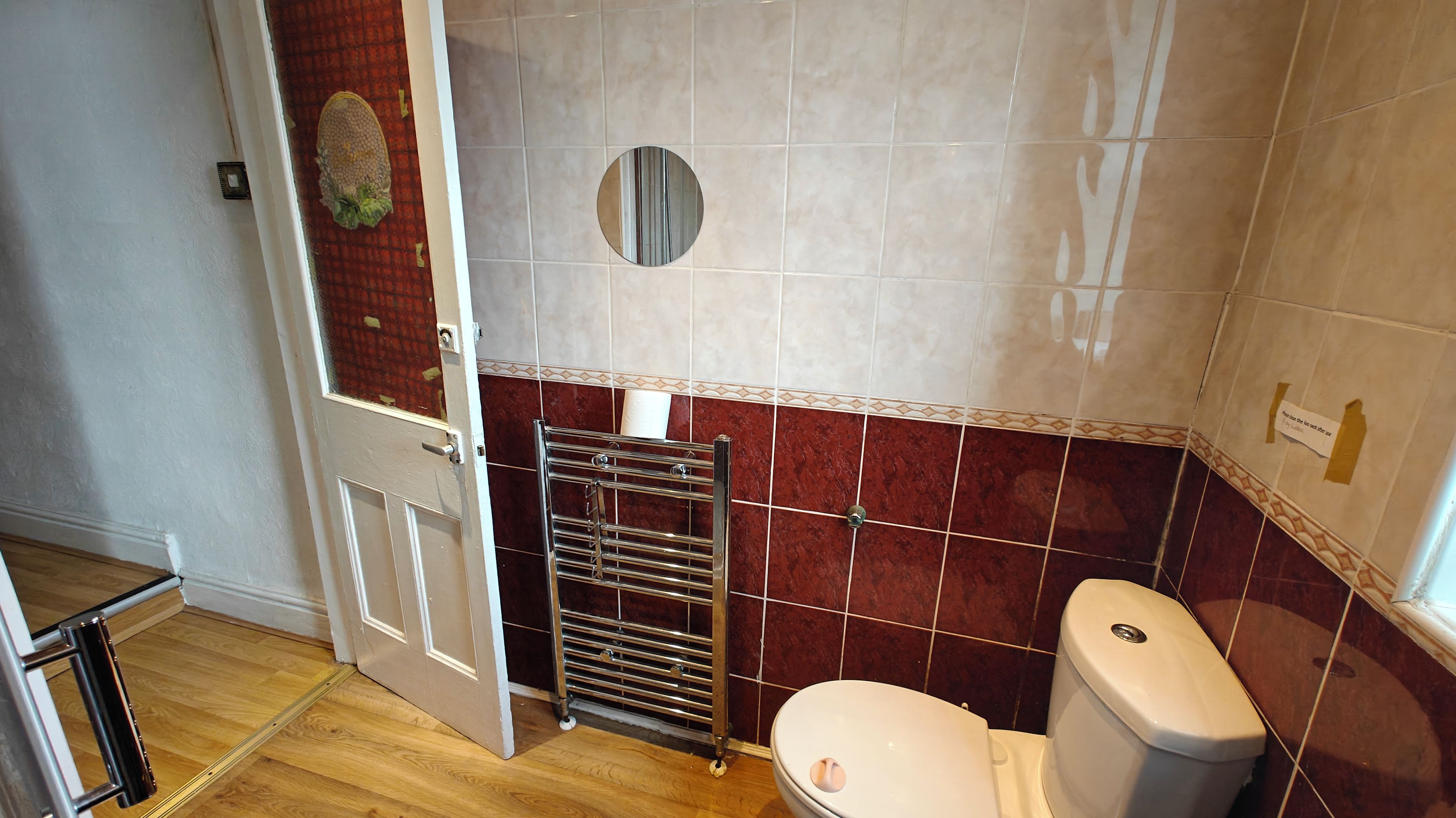 Un baño con inodoro, perchero para toallas y espejo.