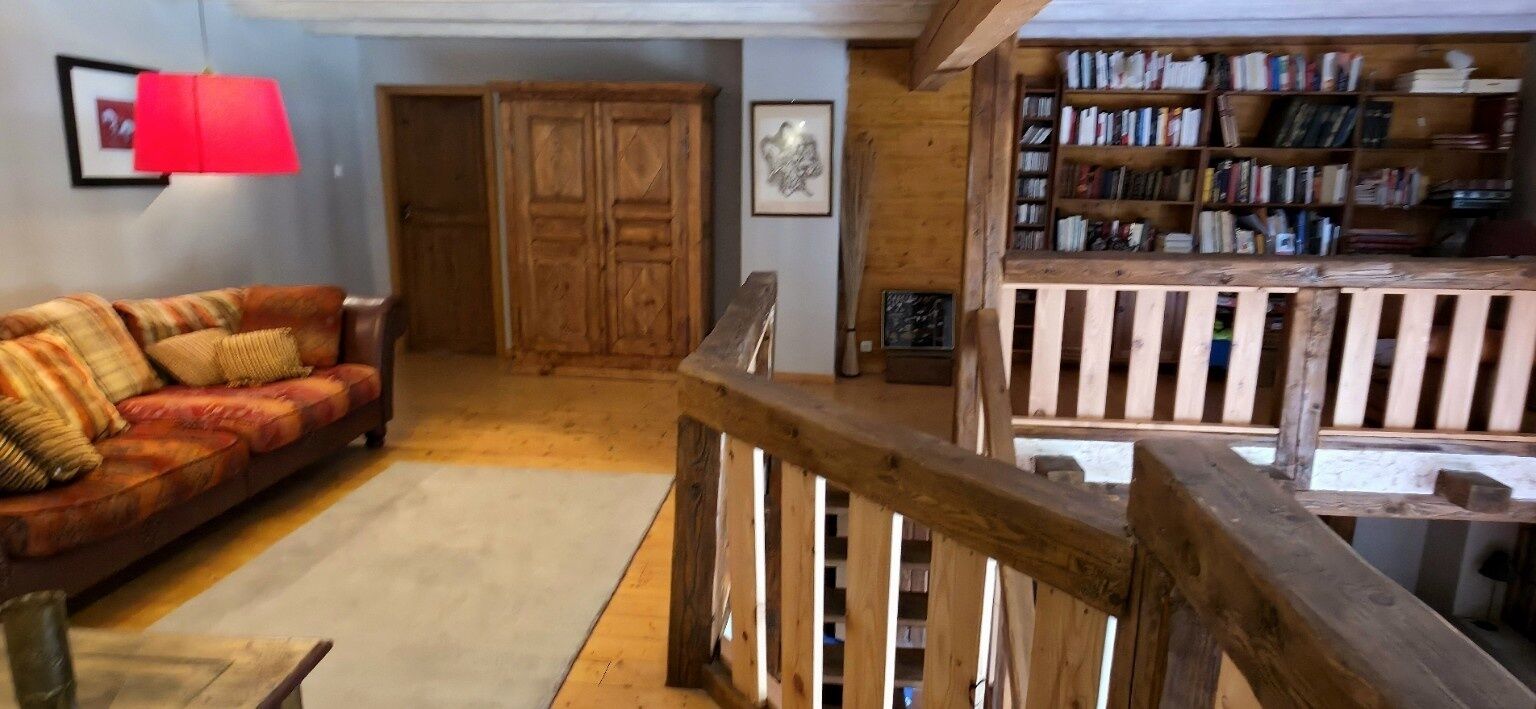 Un salón acogedor con una escalera de madera, una lámpara roja, un sofá y una estantería.