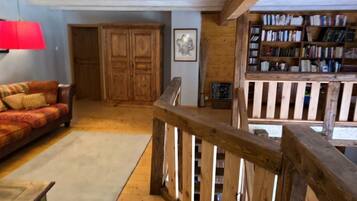 Un salón acogedor con una escalera de madera, una lámpara roja, un sofá y una estantería.