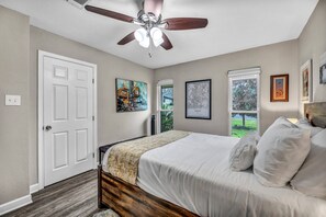 A bedroom with a bed, a ceiling fan, a door, and artwork on the walls. - Hestia: Remodeled 3 Bed gem near downtown (Austin)