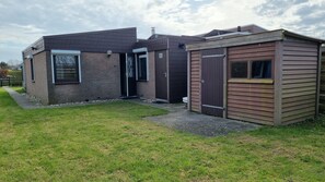 Ein zweigeschossiges Haus mit Ziegelaußenwand, einem kleinen Anbau und einem gepflasterten Auffahrt.
