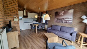 Ein gemütlicher Wohnbereich mit Küchenzeile, Essbereich und einer Sitzecke mit Sofa und Sesseln.