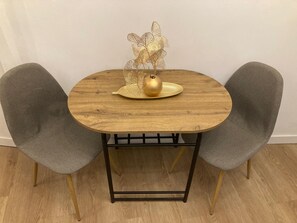 Ein runder Holztisch mit einem goldenen Zierteil und zwei grau gepolsterten Stühlen.