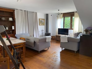 A modern living room with a sofa, a television, and a dining area with a table and chairs. - House with Garden Steps from Cantabria’s Main Beaches (Arguedes)