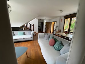 A modern living room with a white sofa, a blue coffee table, and a staircase leading to an upper level. - House with Garden Steps from Cantabria’s Main Beaches (Arguedes)