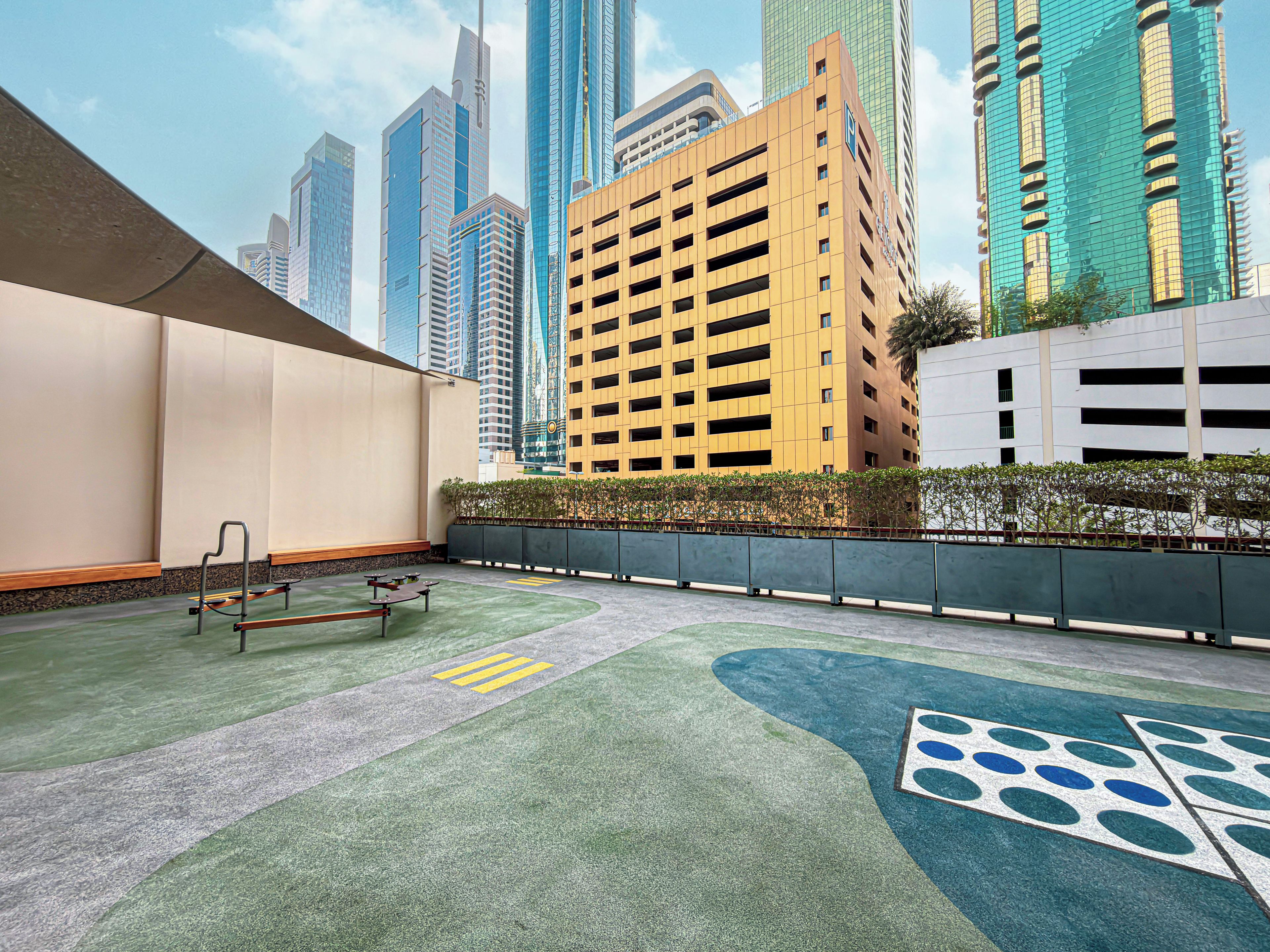 Une terrasse sur le toit, dotée d’un espace salon, offrant une vue sur les immeubles environnants et recouverte d’un sol pavé orné d’un motif géométrique.