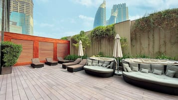 Une terrasse sur le toit avec des sièges extérieurs, un mur en bois et une vue sur les gratte-ciel.