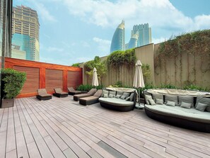 Una terraza en la azotea con mesas al aire libre, un muro de madera y vistas a rascacielos.