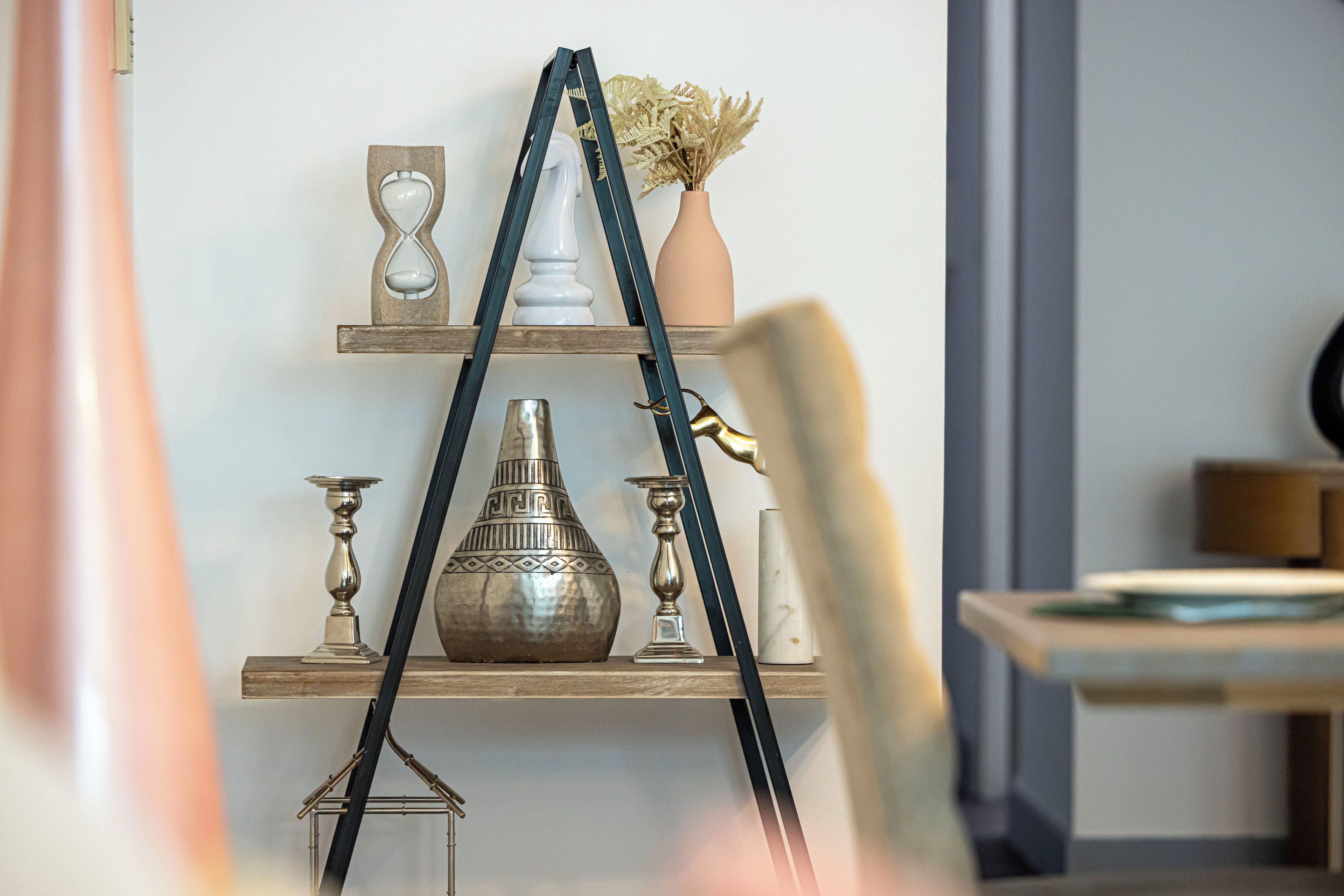 Una repisa con varios objetos decorativos, incluyendo un florero, un candelabro y un jarrón de metal.