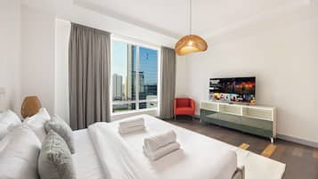 Une chambre d’hôtel avec un grand lit, une télévision, un fauteuil rouge et une vue sur la ville.
