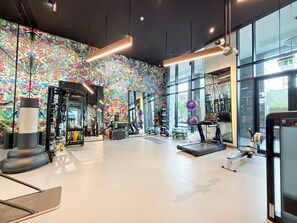Un gimnasio con equipo de ejercicio, un ventanal grande y una pared cubierta de grafitis.
