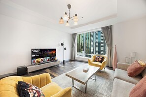 Een moderne woonkamer met een flatscreen televisie, gele banken, een salontafel en een groot raam met uitzicht op de stad.