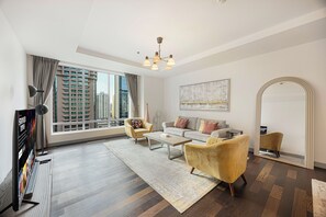 Een moderne woonkamer met een flatscreen televisie, een bank, twee fauteuils, een salontafel en een groot raam met uitzicht op de stad.