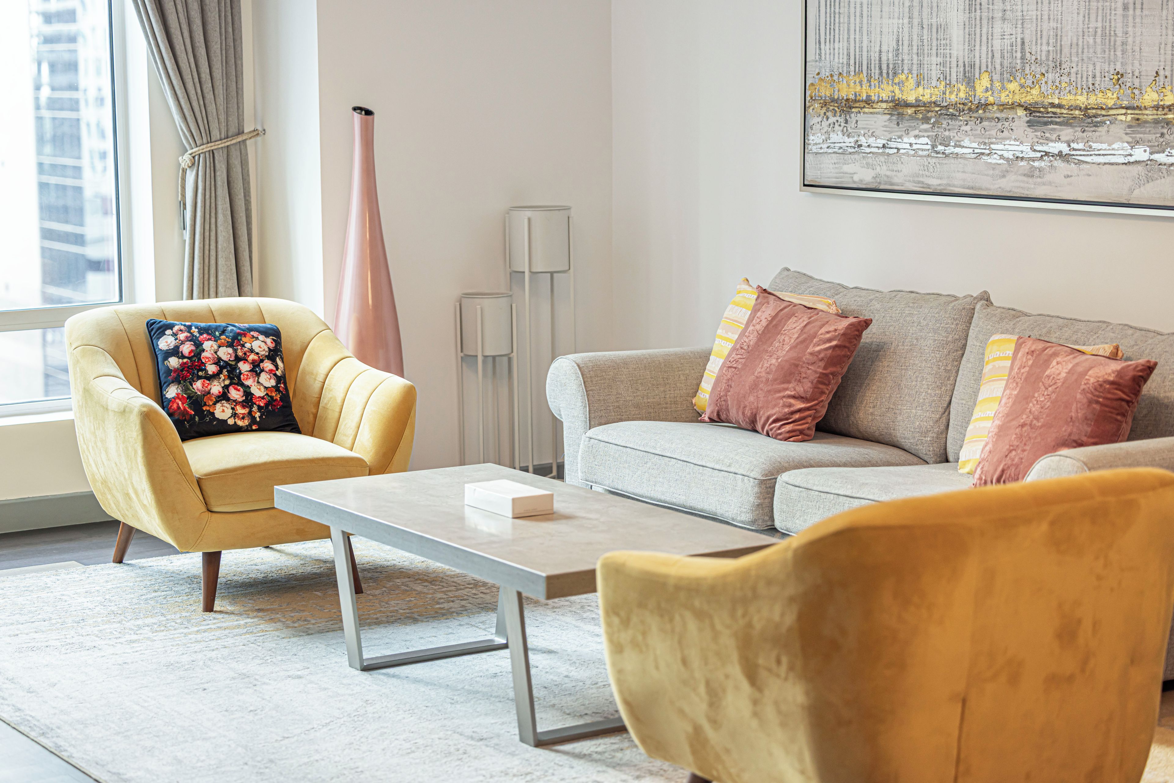 Ein modernes Wohnzimmer mit einem gelben Sessel, einem grauen Sofa und einem Couchtisch.