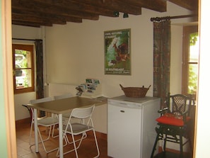 Una piccola cucina con un frigorifero bianco, un tavolo con sedie e un quadro appeso al muro.
