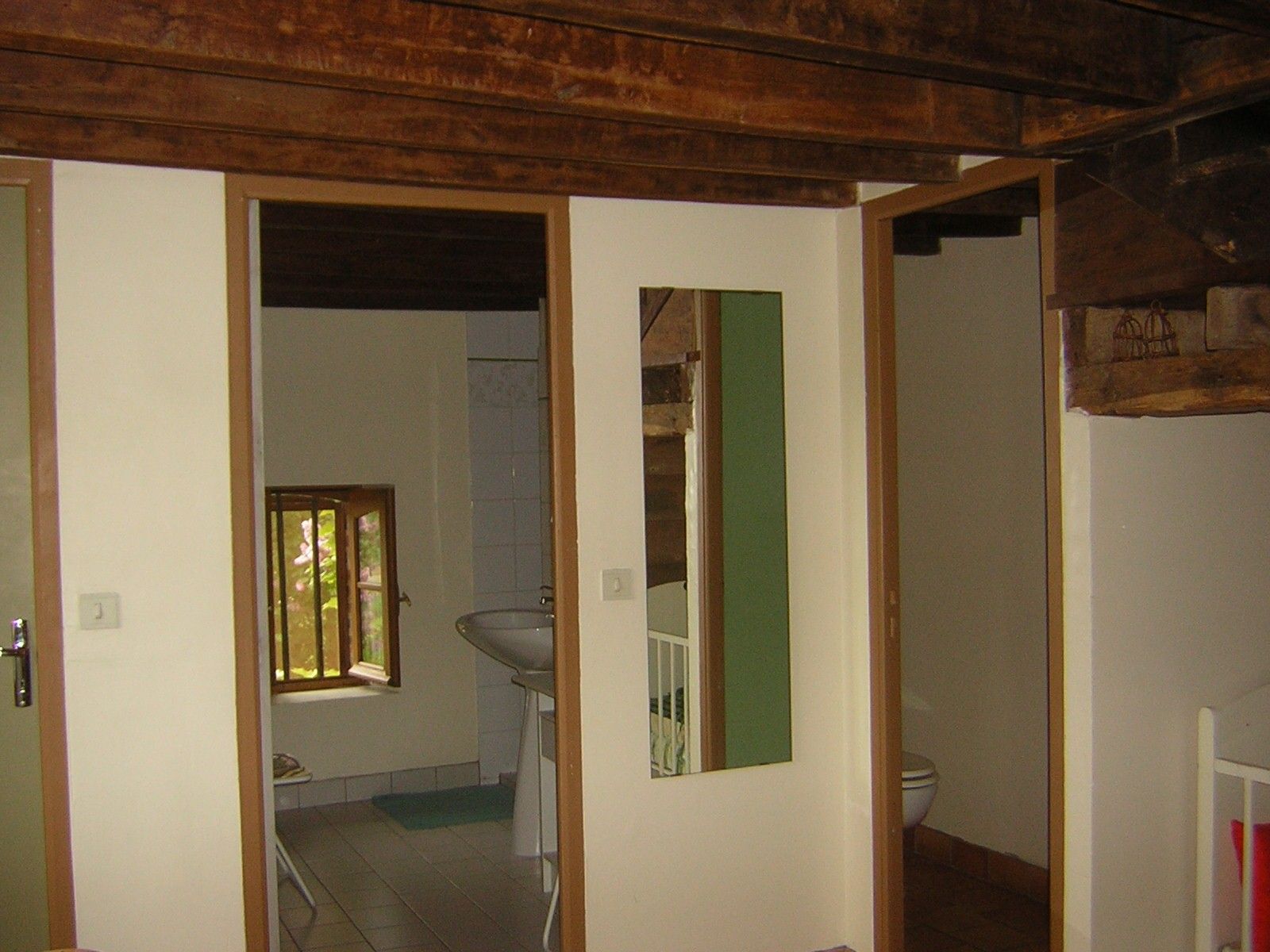 A bathroom with a toilet, sink, and window.