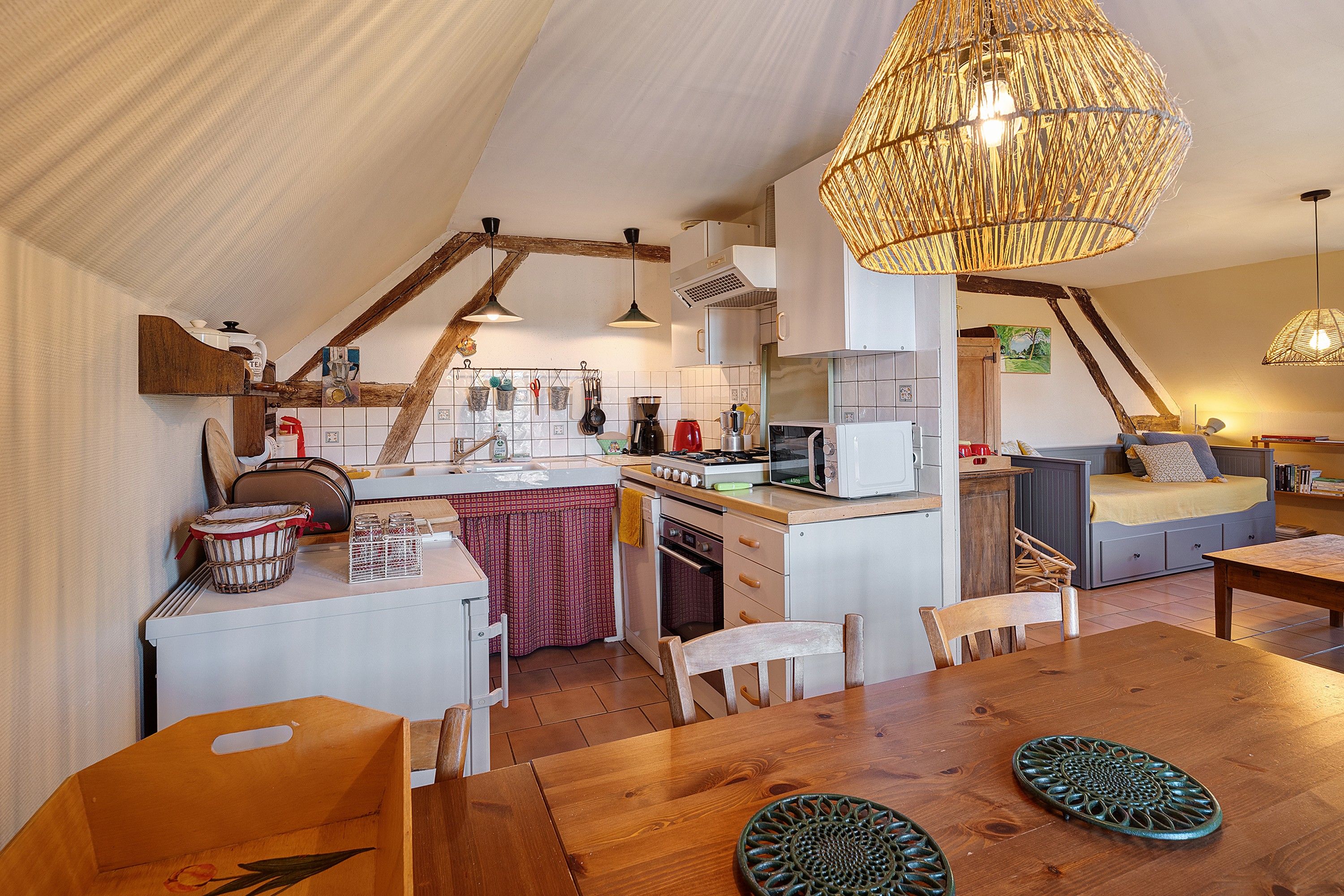 A cozy kitchen with a dining area, wooden furniture, and a hanging light fixture.