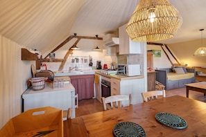 Une cuisine chaleureuse avec un coin repas, des meubles en bois et un luminaire suspendu.