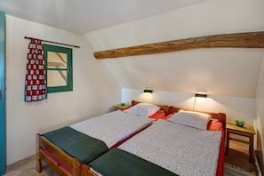 Une chambre avec un lit en bois, une porte verte et une petite table de chevet avec une lampe.