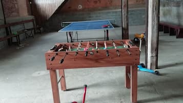 Ein Zimmer mit Tischfußball, Pong-Tisch und einem kleinen roten Dreirad.