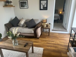 A living room with a sofa, a coffee table, a lamp, and a remote control.