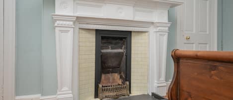 A room with a fireplace, wooden flooring, and a door.