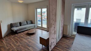 A room with a sofa, a small table, and a large window.