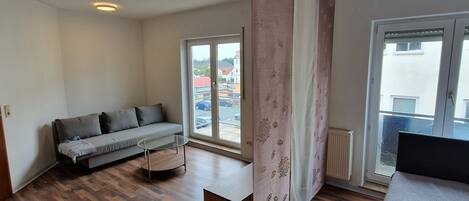 Una habitación con un sofá, una mesita y un ventanal grande.