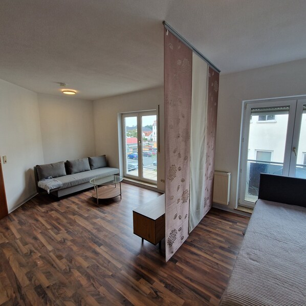 A room with a sofa, a small table, and a large window.