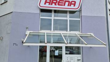 En byggnad med en skylt ovanför ingången där det står ”Fitness Arena”.