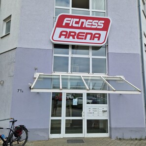 A building with a sign that reads 'Fitness Arena' above the entrance.