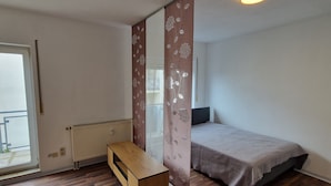 A bedroom with a bed, a wooden bench, a radiator, and a window. - Apartment "Sala Uno" with Wi-Fi (Coswig)