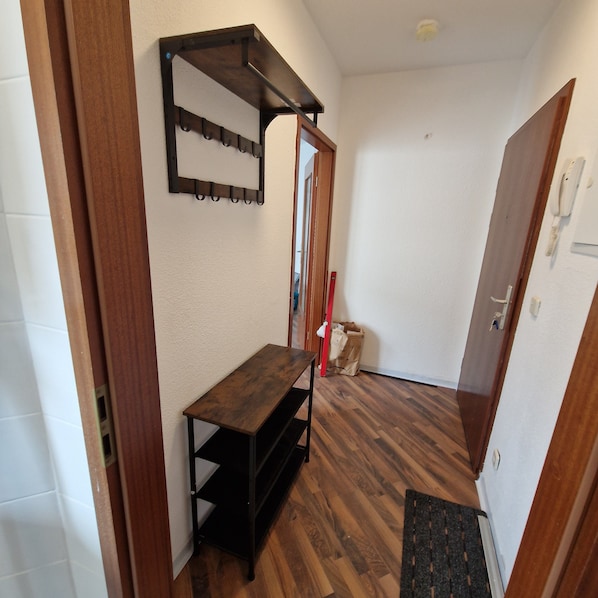 A hallway with a wooden bench, a coat rack, and a door with a phone.