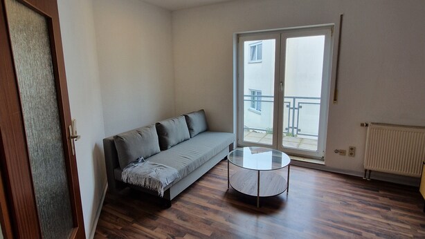 A room with a sofa, a glass coffee table, wooden flooring, a door, and a window with a view. - Apartment "Sala Uno" with Wi-Fi (Coswig)