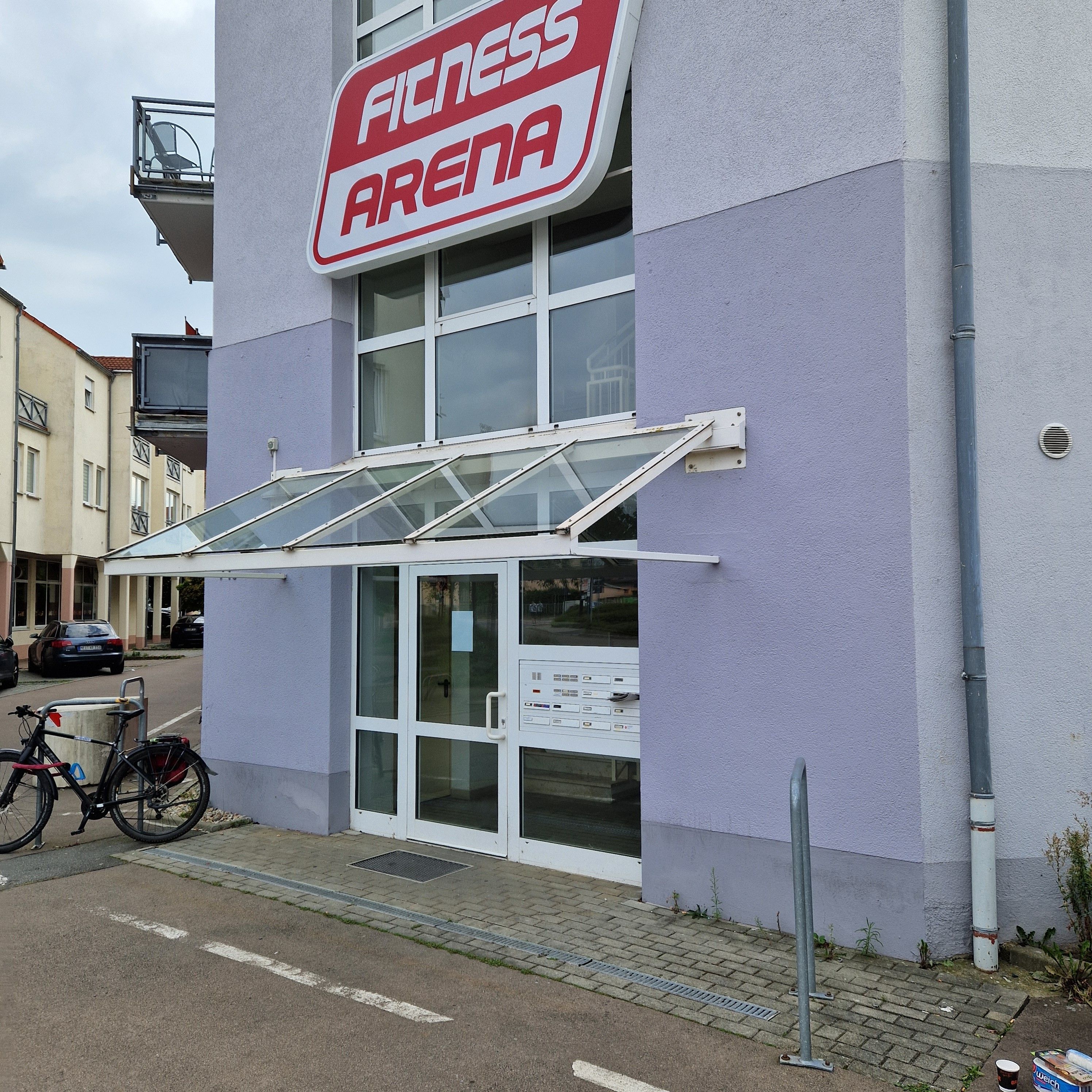 Suuri kyltti, ulkona parkkeerattu polkupyörä ja kirkas taivas – tässä on kuntoilukeskus.