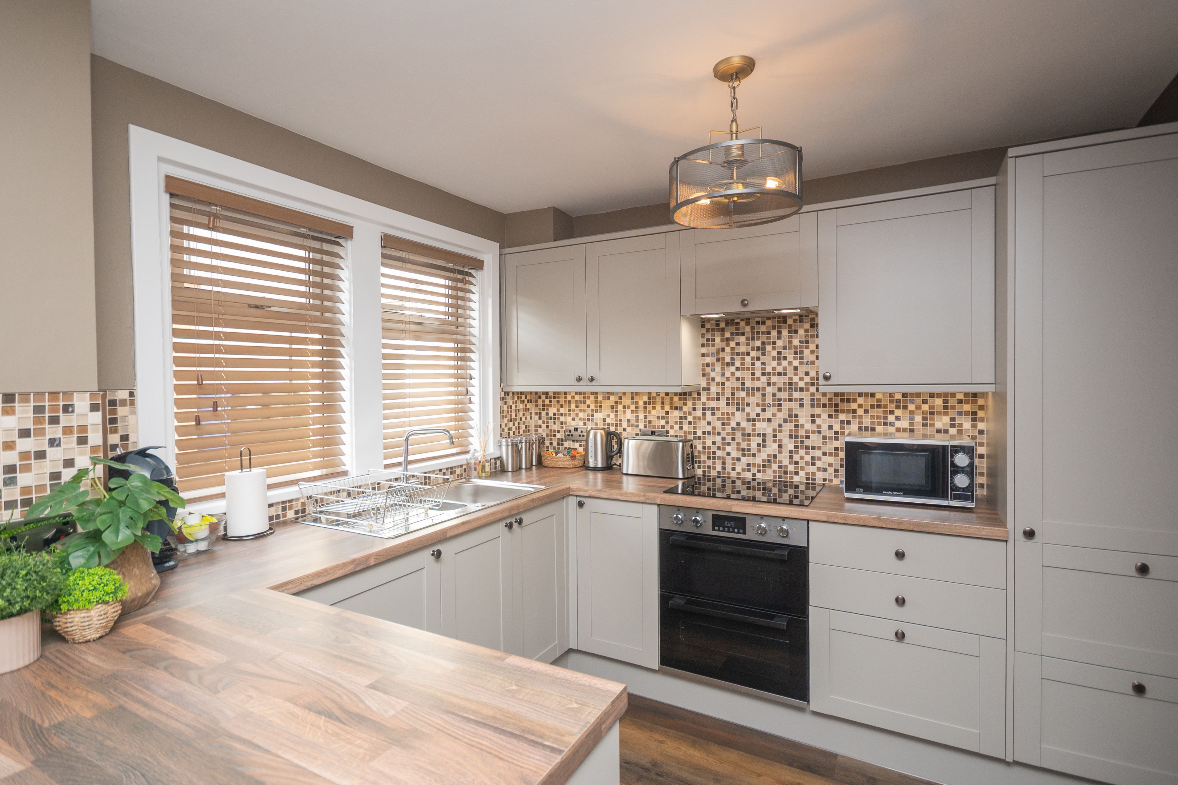A modern kitchen with white cabinets, a wooden countertop, a built-in oven, and a microwave.