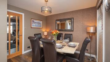 A dining room with a brick wall, a framed picture, a chandelier, and a mirror.